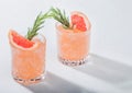 Glasses of refreshing summer red grapefruit cocktail with ice cubes, fruit slice and rosemary on white background Royalty Free Stock Photo