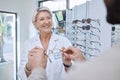 Glasses, retail store and sale of a senior eye doctor holding a frame to help customer shopping. Happy optometrist, shop