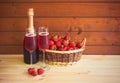 Glasses of rose champagne, bottle of rose champagne and fresh strawberry in wicker basket on wooden table near wooden wall Royalty Free Stock Photo