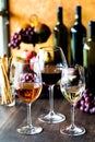 Glasses of rose, red and white wine with wine bottles and fruit in behind. Royalty Free Stock Photo
