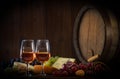 Glasses of rose wine cheeses grapesand barrel on brown wooden background Royalty Free Stock Photo