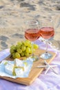 Glasses with rose wine and snacks for beach picnic on sand outdoors Royalty Free Stock Photo