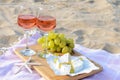 Glasses with rose wine and snacks for beach picnic on sand outdoors Royalty Free Stock Photo
