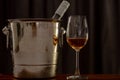 A glasses of Rose wine on wooden table with a bottle in wine chiller bucket