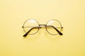 Glasses in round thin metal frame isolated on yellow surface.