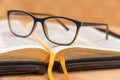 Glasses for sight lie on the Bible, the Bible in leather black cover with tabs lies on the table