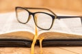 Glasses for sight lie on the Bible, the Bible in leather black cover with tabs lies on the table Royalty Free Stock Photo