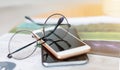 Glasses and smart phone on a book at coffee shop. Royalty Free Stock Photo