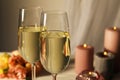 Glasses of sparkling wine, flowers and burning candles on white table, closeup Royalty Free Stock Photo