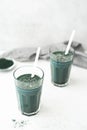 2 glasses of spirulina algae detox smoothie on white table