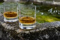 Glasses of strong scotch single malt whisky served on old stone reservoir for water from mountain spring
