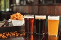 Glasses of tasty beer and snacks on wooden table