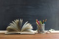 Glasses teacher books and a stand with pencils on the table, on the background of a blackboard with chalk. The concept of the teac