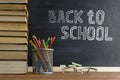 Glasses teacher books and a stand with pencils on the table, on the background of a blackboard with chalk. The concept of the Royalty Free Stock Photo