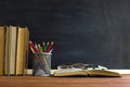 Glasses teacher books and a stand with pencils on the table, on the background of a blackboard with chalk. The concept of the teac Royalty Free Stock Photo