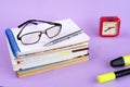 Glasses, textbooks, notebook, pens, markers and a red watch on a lilac background. Schooll concept Royalty Free Stock Photo