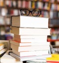 Glasses on top of stack of books lying on table in bookstore