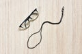 Glasses transparent dark blue frame with black eyeglasses strap make shape like sperm on a wooden background, a