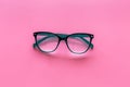 Glasses with transparent optical lenses on pink background top view space for text closeup