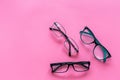 Glasses with transparent optical lenses on pink background top view space for text