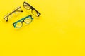 Glasses with transparent optical lenses on yellow background top view copy space