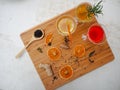 Multiple glasses with a variety of homemade flavored kombucha tea on a wooden cutting board and a white background