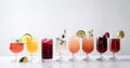 Glasses with various alcoholic cocktails in a row with fruits, white background. AI generated