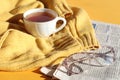 Glasses for vision with a cup of hot tea on a knitted sweater, a fresh newspaper, a side view-the concept of a cozy pastime for Royalty Free Stock Photo