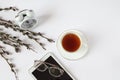 Glasses for vision lie on the tablet against the background of a cup of tea and an alarm clock, willow branches, a white Royalty Free Stock Photo