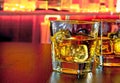 Glasses of whiskey with ice on bar table near whiskey bottle on warm atmosphere Royalty Free Stock Photo