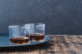 Glasses of whiskey with ice cubes on a black tray and wooden table/Two Glasses of whiskey with ice cubes on a black tray and Royalty Free Stock Photo