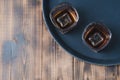 Glasses of whiskey with ice cubes on a black tray and wooden table/Two Glasses of whiskey with ice cubes on a black tray and Royalty Free Stock Photo