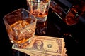 Glasses of whiskey near bottle and dollars on a black table. Western theme style