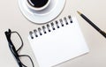 Glasses, a white cup with coffee, a blank white notepad for inserting text and a ballpoint pen lie on a light background. Flat lay Royalty Free Stock Photo