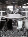 Glasses and white plates in a modern dishwasher machine