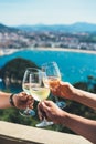 Glasses white wine in hands outdoor seascape holidays, romantic toast with alcohol, happy people cheering fun vacation