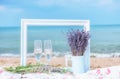 Glasses with white wine and lavender flowers on the pstilka on the beach by the sea. Summer light still life, the atmosphere of re Royalty Free Stock Photo