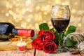 A glasses of wine, roses, gift and burning candle