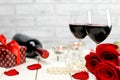 A glasses of wine, roses, gift and burning candles