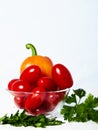 Glasss cup with tomatoes and peppers on a white table with parsley.