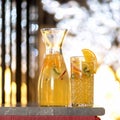 Glassware with citrus lemonade drink on blurred sunset background. Healthy fresh juice or soft drink. Bright colors of Royalty Free Stock Photo