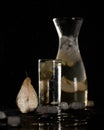 Glassware with cool drink and half of pear on black background. Glass and jug with Pear-lemon iced lemonade. Soft focus Royalty Free Stock Photo