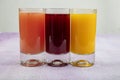 Glassware with refreshing citrus fruits cocktail on white wooden background. Antioxidant juices of Pomegranate Juice, Orange Juice