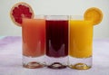 Glassware with refreshing citrus fruits cocktail on white wooden background. Antioxidant juices of Pomegranate Juice, Orange Juice