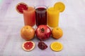 Glassware with refreshing citrus fruits cocktail on white wooden background. Antioxidant juices of Pomegranate Juice, Orange Juice