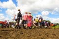 Glastonbury Festival crowds walk through mud beneath sunny sky