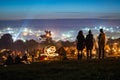 Glastonbury Festival. 30th June 2014. Three young woman looking across the lights and crowds of Glastonbury Festival at night. Wit