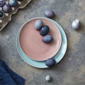 Glazed ceramic plate in a color of Living Coral Pantone with painted violet Easter eggs on a gray stone background, copy Royalty Free Stock Photo