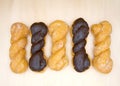 glazed and chocolate covered twist donuts on a light wood surface, alternating pattern