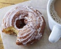 Glazed cruller donut on wax paper next to a mug of hot coffee Royalty Free Stock Photo
